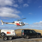 Photo of a helicopter hovering beside a four by four, towing a Fuel Proof Aviation Highway Tow Bowser