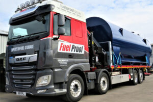 A dark blue Bulk Horizontal Diesel Tank sits loaded and strapped on a bright red branded Fuel Proof truck, ready for delivery to our customers.