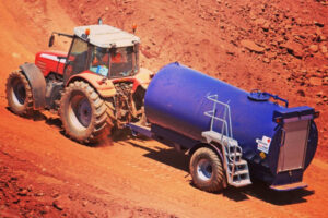 A tractor pulls a Fuel Proof Site Tow Diesel Bowser in a red-earth quarry environment